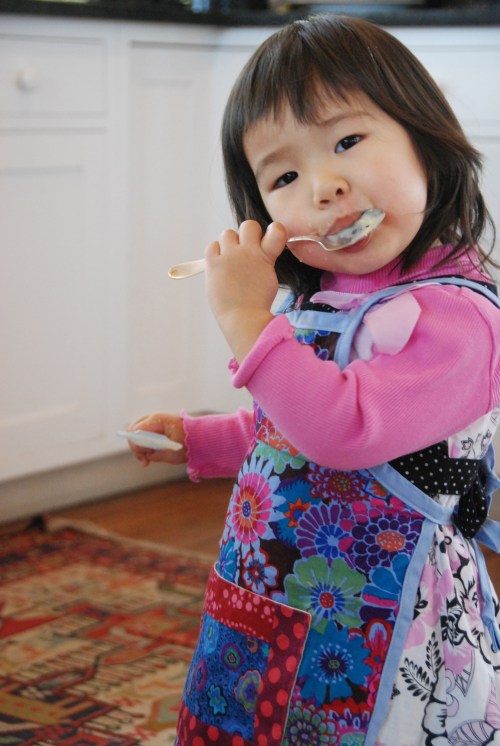 Josie licking icing in her new apron!